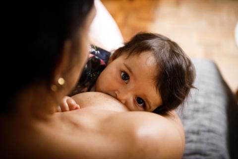 A baby with a full head of dark hair breastfeeds