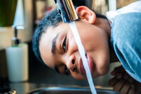 Boy drinks from kitchen faucet