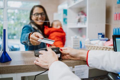 A woman with a baby pays for prescription medications at the pharmacy