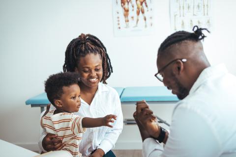 A young maternal and child health care provider interacts pleasantly with a mother and infant