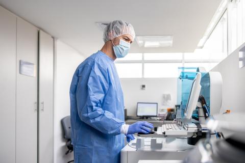 A worker in a lab submits cancer data electronically
