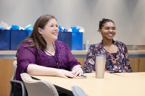 Two people sitting next to each other at a table watching a presentation.